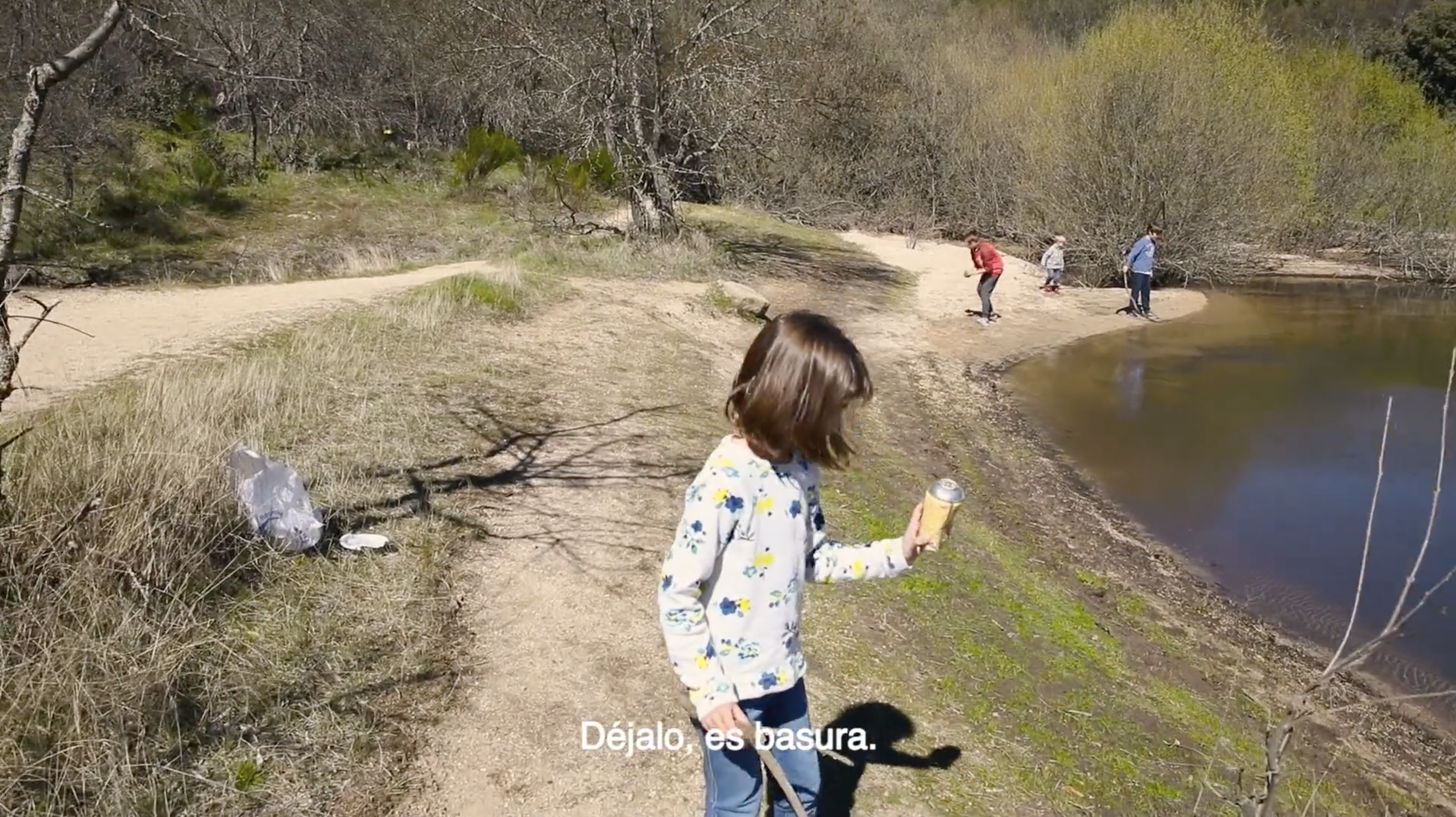 A child learning to collect litter in a natural space.